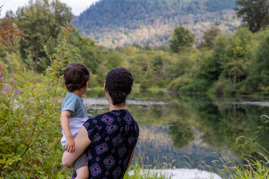 Mother Holding Child Looking Over Lake At Great Blue Heron Nature Reserve, Chilliwack, BC Canada
