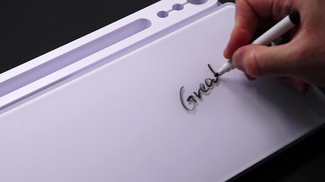 European male hand writing great job on whiteboard with black pen and erases it with white sponge afterwards for seamless looping message writing on whiteboard. Positive feedback from boss great work.