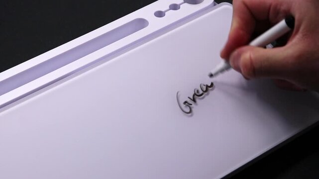 European male hand writing great work on whiteboard with black pen and erases it with white sponge afterwards for seamless looping message writing on whiteboard. Positive feedback from boss good work.