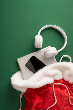 Merry Christmas Santa present bag with headphones phone and laptop for New Year celebrations on vertical green background