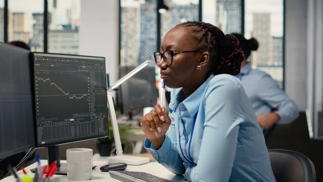 Financial analyst in a prop firm researches stock market shares, reading investment analysis reports on a computer to support trading decisions.