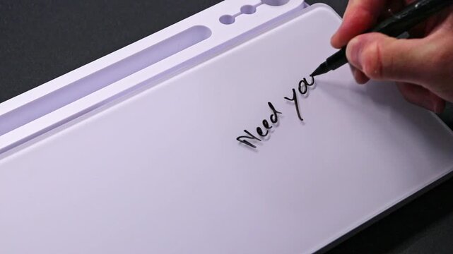 European male hand writing need your help on whiteboard with black pen and erases it with white sponge afterwards for seamless looping message writing on whiteboard. Help needed support text.