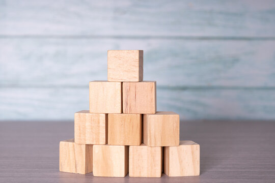 Wooden cubes stacked in pyramid shape, foundation and teamwork background