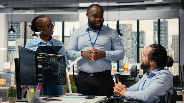 Trader with a disability and colleagues celebrate investment gains with a high five after reaching milestones, as the man with paraplegia and prop firm coworkers mark successful trading operations.