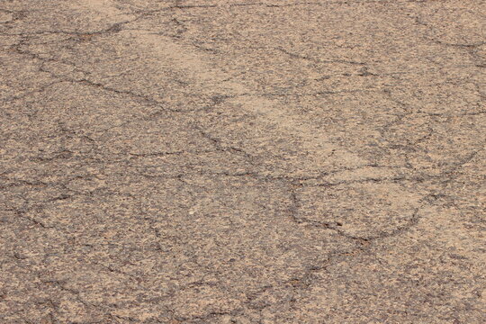 Cracked and Worn Asphalt Road in a Dry Landscape