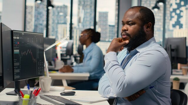 Day trader analyzes stock market trends and price charts while making buy and sell decisions, as a financial expert places client orders using trading software on a workstation in the office.