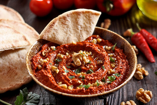 Muhammara dip in a bowl served with pita bread and walnuts. Middle Eastern mezze.
Traditional Middle Eastern muhammara dip made of roasted red peppers, walnuts, pomegranate molasses, and olive oil. 