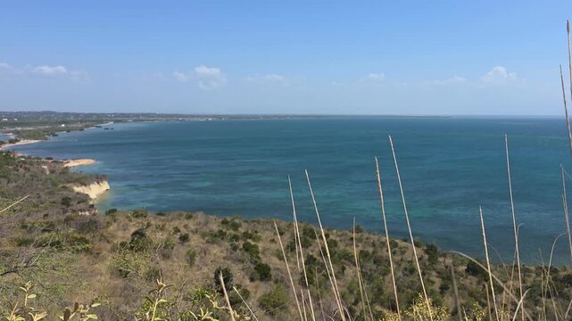 Panoramic view from El Morro, Montecristi, Dominican Republic &mdash; a dramatic coastal cliff overlooking the deep blue Caribbean Sea and a natural bay. Dry coastal vegetation and wild grass frame the scen
