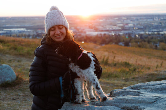 Woman and her dog sharing a moment together at dawn in a park