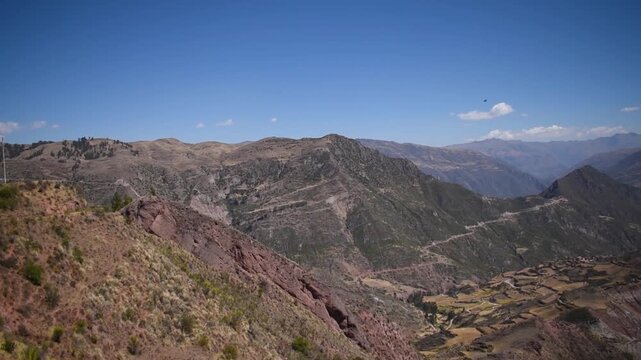 Green shrubs framing a vast Andean mountain valley in Paruro, Cusco, Peru.