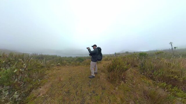 Hiker photographer shooting foggy paramo landscape in colombia