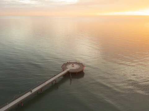 Aerial view of a pier extending into the calm sea during a golden sunset in Iceland.
