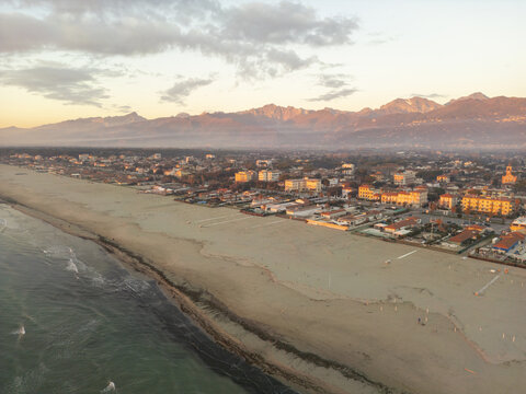 Aerial view of a coastal town with sandy beaches and mountains in the background in Italy.