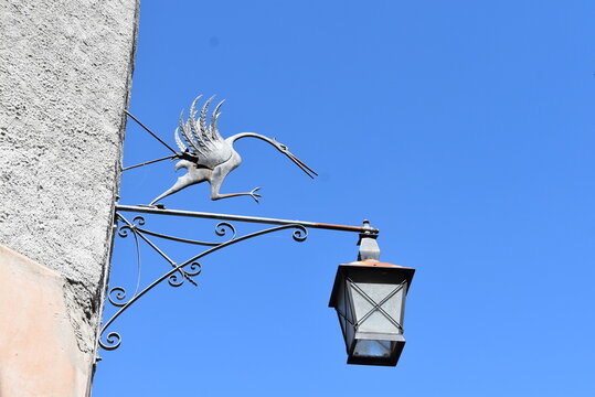 Lampadaire mural sur une fa&ccedil;ade &agrave; Gruy&egrave;re. Il est orn&eacute; d'une grue, animal embl&egrave;me de la ville.
