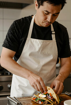 Home cooking and healthy eating, man preparing fresh tacos with vegetables and meat in a modern kitchen