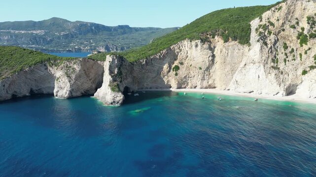 Aerial high angle descent revealing turquoise water and bright white cliffs at Chomi Beach near Paleokastritsa