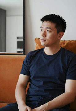 Thoughtful young asian man relaxing at home, contemplation and mental well being, casual lifestyle portrait indoors