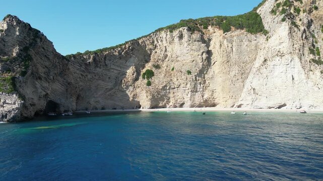 4K Aerial 180‑degree panorama shot over Chomi Beach with turquoise water and white cliffs near Paleokastritsa, Corfu, Greece