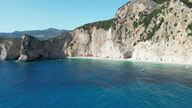 4K Rising aerial view of Chomi Beach and anchored boats near Paleokastritsa, Corfu