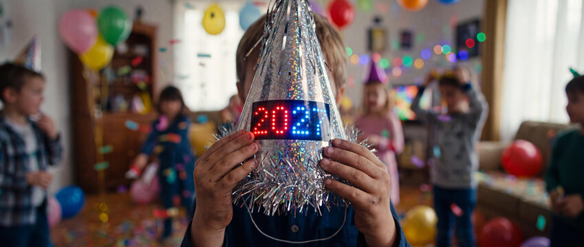 Boy Holding Silver Party Hat with 2027 Digital Number at Festive Kids Celebration