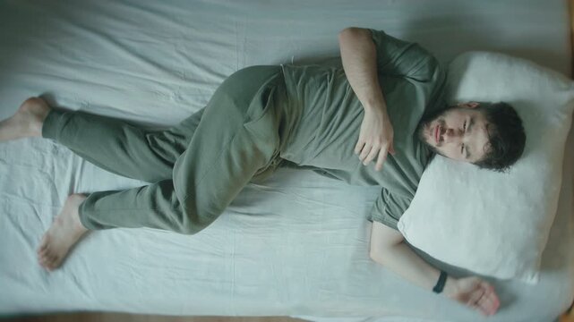 Young Man Startled Awake From Sleep, Jolting In Bed At Home