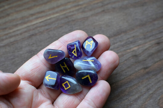 Scandinavian runes made of natural amethyst stone in hand