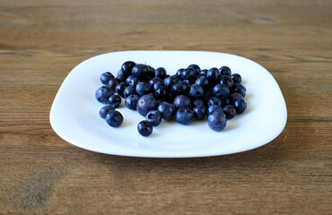 Bilberries from Forest Arranged on White Plate Sitting on Wooden Surface © yaviki