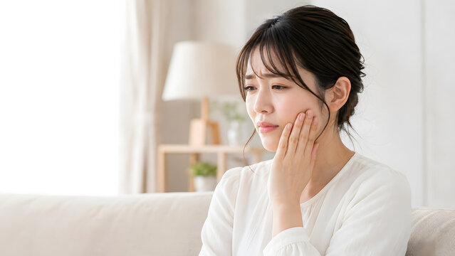 歯の痛みで頬を押さえる若い女性と広いコピースペース