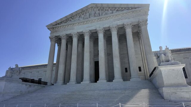 Three-quarter tilt up establishing shot of the United States Supreme Court Building, showcasing its marble steps, columns and classical architecture in Washington, DC. 15337  