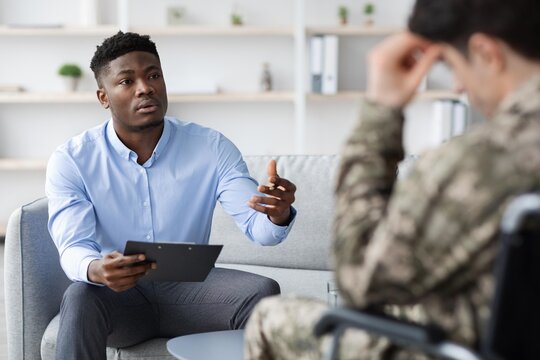 Focused Black Male Therapist Engaging In Conversation With A Veteran In A Professional Office Setting, Discussing Mental Health Challenges And Counseling Options. Mental Health And Counseling Concept.
