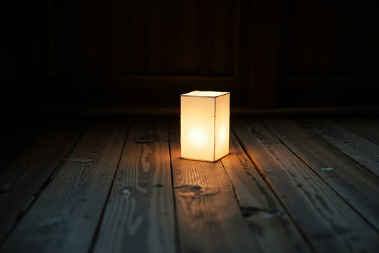 Square Paper Lantern Glowing on an Old Wooden Floor