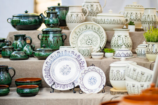 Handmade ceramic cups, bowls and vases displayed for sale at an outdoor craft market. Artisan pottery with unique glazes represents traditional craftsmanship and local small business.