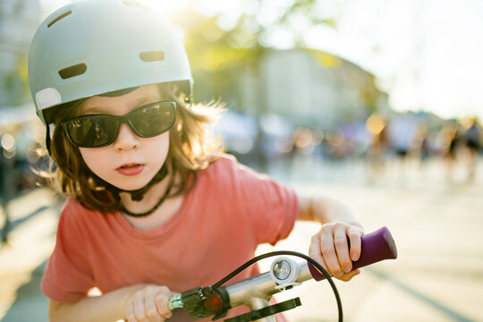 Cool young boy wearing helmet and sunglasses rides a kick scooter in the city on a sunny day. Active urban childhood, outdoor fun and safe mobility.