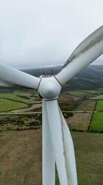 Aerial view of Parque eolico Neda wind turbine hub and blades over green fields in the countryside of Lugo, Lugo, Spain.