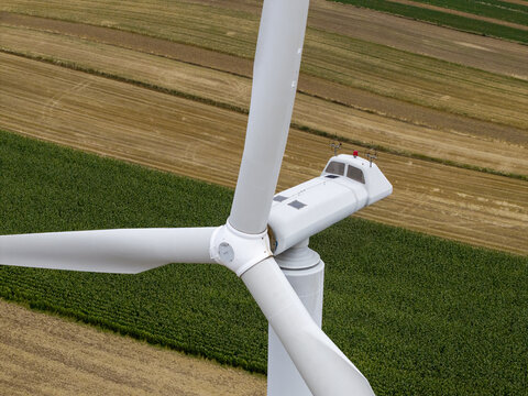 Aerial view of a wind turbine nacelle and blades set against a backdrop of agricultural fields in Poland.
