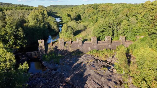 Aerial view of the historic Yngeredsfors powerplant ruins known as Doda Fallet, surrounded by forests and river flowing through rocky terrain in Vessigebro, Hallands lan, Sweden.