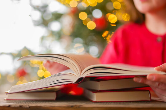 Christmas reading. Woman Reading Books Against Christmas Tree with Festive Bokeh During Christmas Winter Holidays.literacy campaigns,bookstore promotions