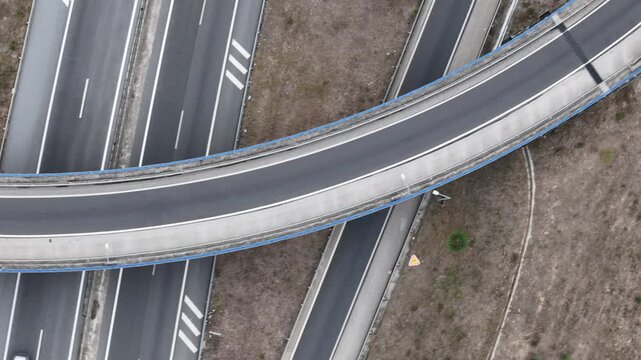 Aerial view of the A5 highway interchange featuring curved asphalt roads and concrete overpasses surrounded by dry vegetation in Cascais, Lisboa, Portugal.