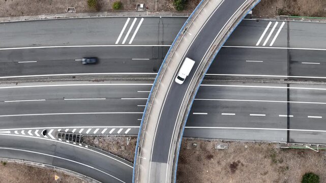 Aerial view of a white car driving on the A5 highway interchange with road markings and asphalt lanes in Cascais, Lisboa, Portugal.