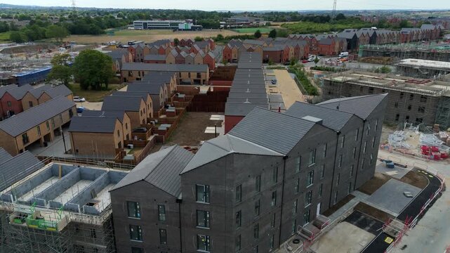 Aerial view of modern residential housing development under construction with dark brick buildings and surrounding infrastructure in Luton, England, United Kingdom.