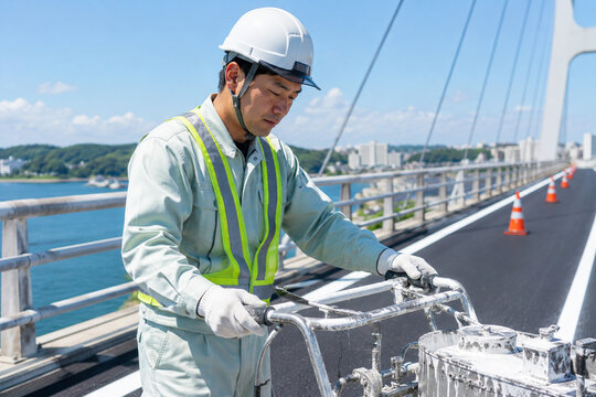 橋上で車線を塗装する作業員