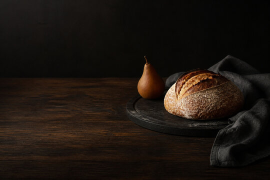 Rustic autumn bread and pear on a dark dining table