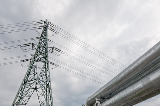 a pipeline and a power transmission tower against a gray sky