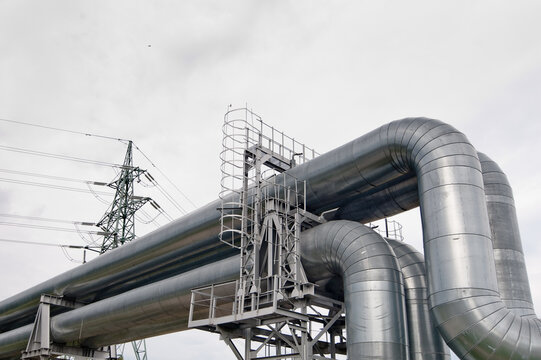 a pipeline and a power transmission tower against a gray sky