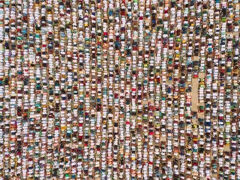 Aerial view of large crowd of people gathered for Eid prayer, organized in neat rows on colorful prayer mats in an open field in Narayanganj, Dhaka, Bangladesh.