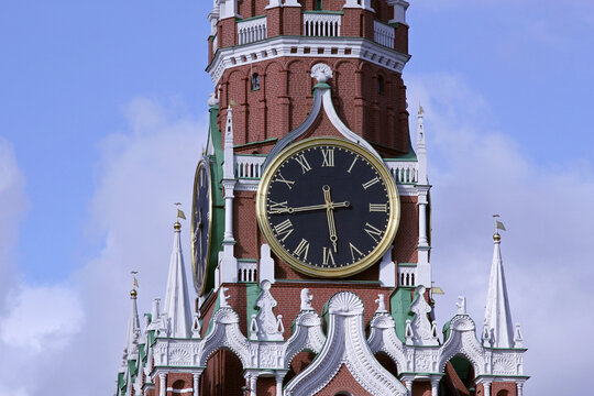 Close-up of Spasskaya Tower clock face on Kremlin wall against cloudy blue sky in Moscow