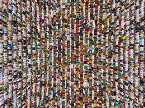 Aerial view of a large crowd of people gathered for Eid prayer on colorful prayer mats arranged in neat rows in Narayanganj, Dhaka, Bangladesh.