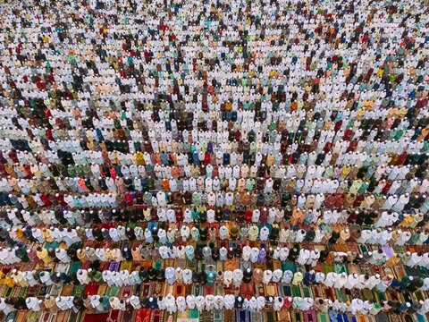 Aerial view of a large crowd of men performing Eid prayer in organized rows on colorful prayer mats in Narayanganj, Dhaka, Bangladesh.