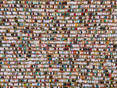 Aerial view of thousands of people gathered for Eid prayer, arranged in neat rows on prayer mats in an open field in Narayanganj, Dhaka, Bangladesh.