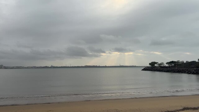Cloudy coastal landscape in Vitória, Espírito Santo, Brazil, with calm sea, sandy beach and sunlight breaking through dramatic clouds